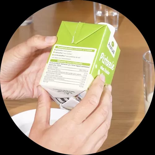 Zwei Hände halten eine Packung Alnatura Pistaziendrink ohne Zucker prüfend hoch.