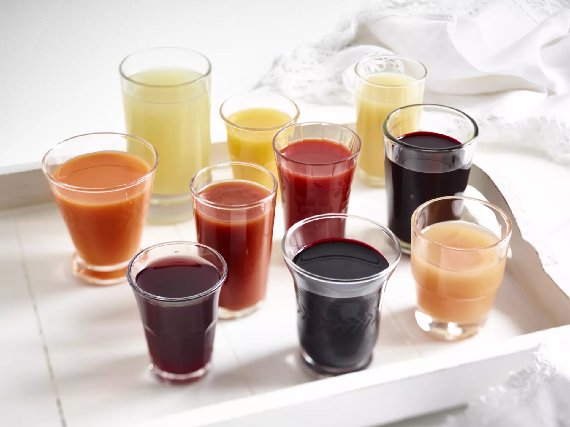 Auf Tablett stehen 10 Gläser mit unterschiedlichen Fruchtsäften gefüllt.