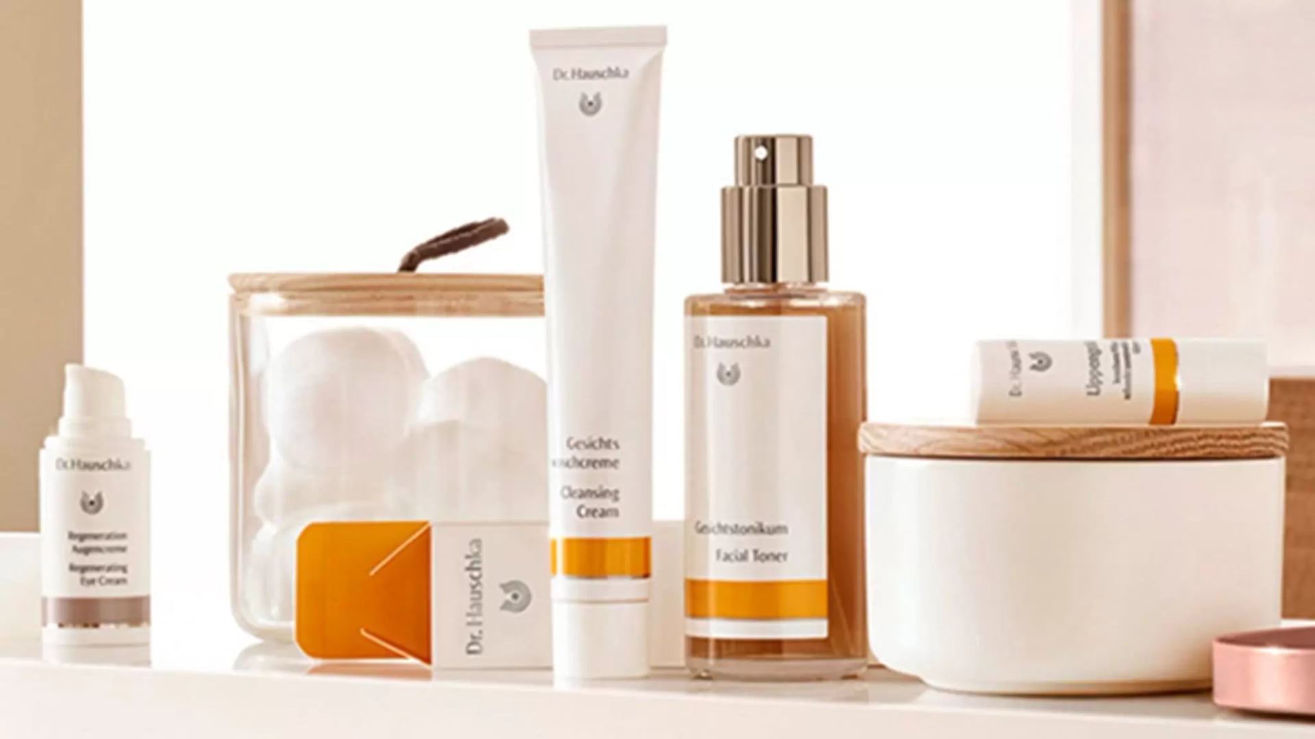 Mehrere Hautpflegeprodukte von Dr. Hauschka auf einer hellen Oberfläche, darunter Gesichtscreme, Gesichtstonikum und ein Tiegel mit Holzdeckel.