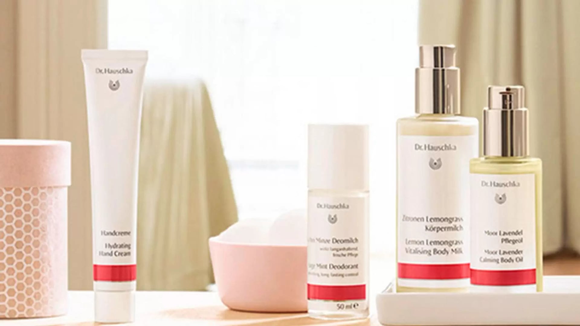 Kosmetikprodukte von Dr. Hauschka auf einem hellen Untergrund mit Handcreme, Deodorant, Körpermilch und Pflegeöl.