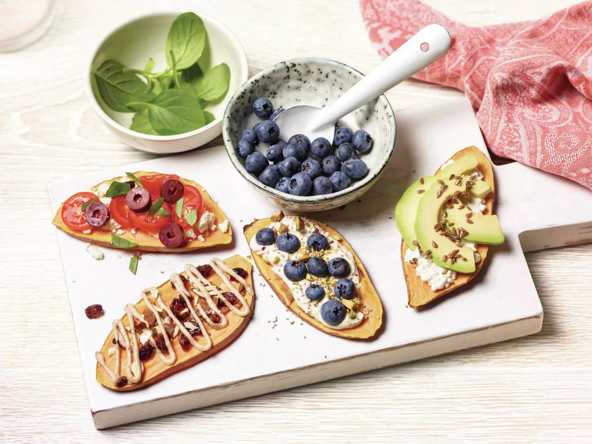 Getoastete Süßkartoffel Scheiben mit Avocado-, Tomaten-, und Heidelbeeren Belag.