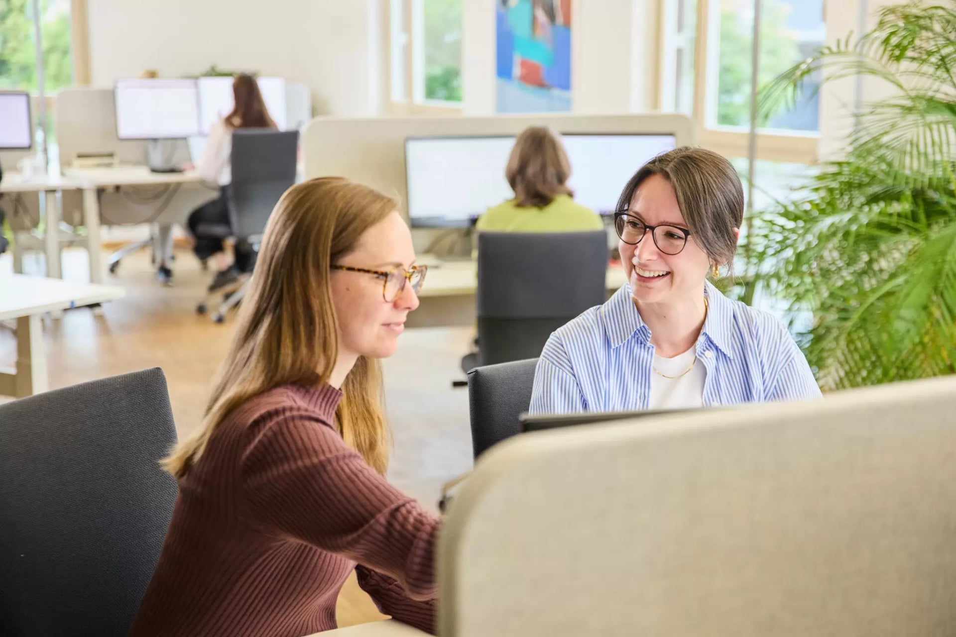 Mitarbeiterinnen und Mitarbeiter in den Büroräumen beim Arbeiten